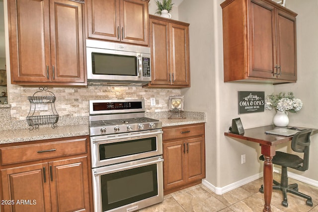 kitchen with appliances with stainless steel finishes, light stone countertops, light tile patterned floors, and backsplash