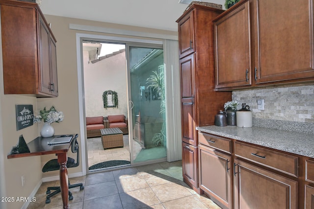 interior space with tasteful backsplash, light stone counters, and light tile patterned floors