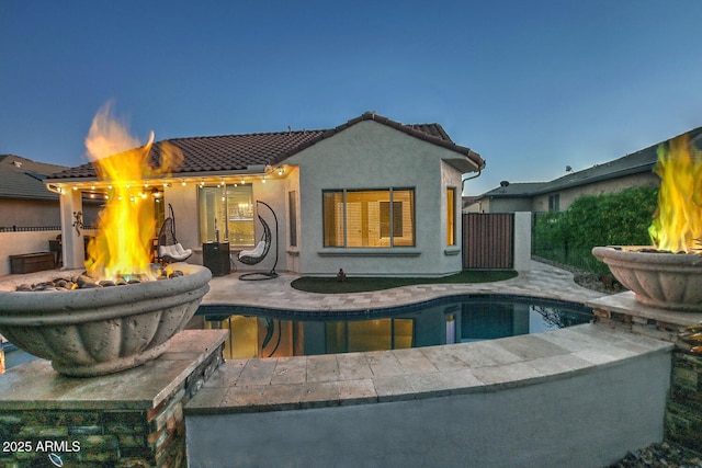 back house at dusk featuring an outdoor fire pit and a patio area