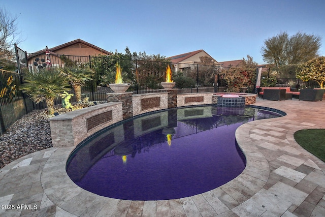 view of patio / terrace featuring a swimming pool with hot tub and an outdoor fire pit