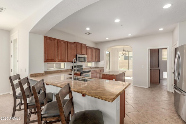 kitchen featuring light tile patterned flooring, a kitchen island, stainless steel appliances, arched walkways, and recessed lighting