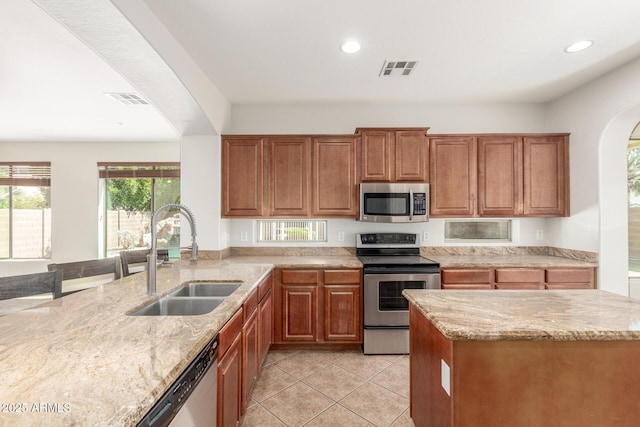 kitchen with visible vents, light stone counters, a sink, and stainless steel appliances