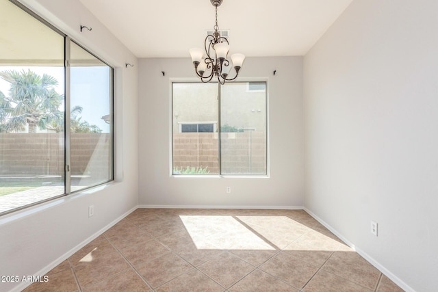 spare room featuring baseboards, light tile patterned floors, and a chandelier