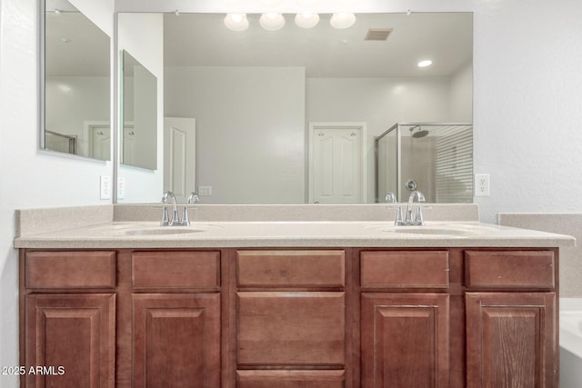 bathroom with double vanity, a sink, a stall shower, and visible vents