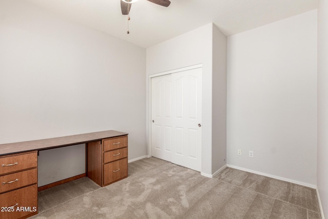 unfurnished office featuring light carpet, baseboards, and a ceiling fan