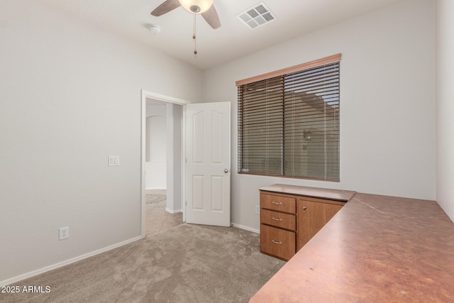 unfurnished office featuring light carpet, baseboards, visible vents, and a ceiling fan