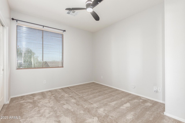 carpeted spare room featuring baseboards, ceiling fan, and visible vents