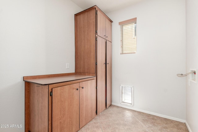 hall featuring baseboards and light tile patterned floors