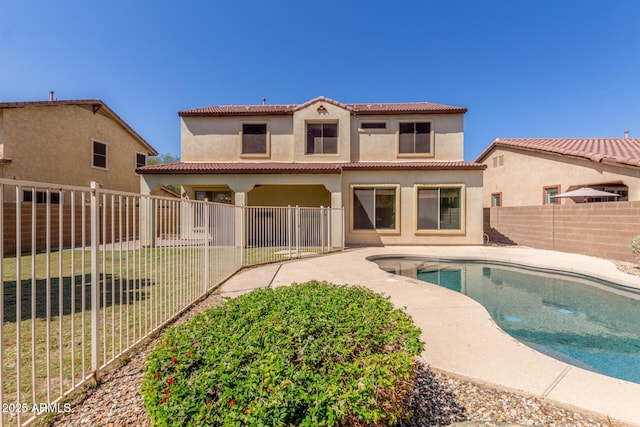 back of house featuring a tiled roof, a patio, a fenced in pool, a fenced backyard, and stucco siding