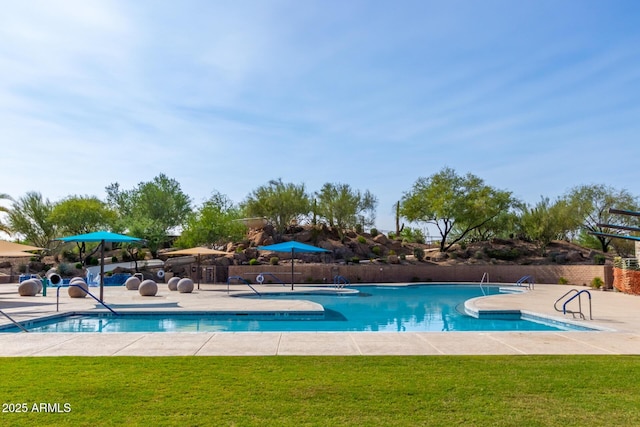 pool with a patio, fence, and a yard