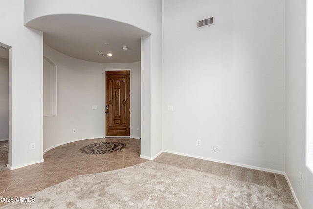 interior space with baseboards, arched walkways, visible vents, and tile patterned floors