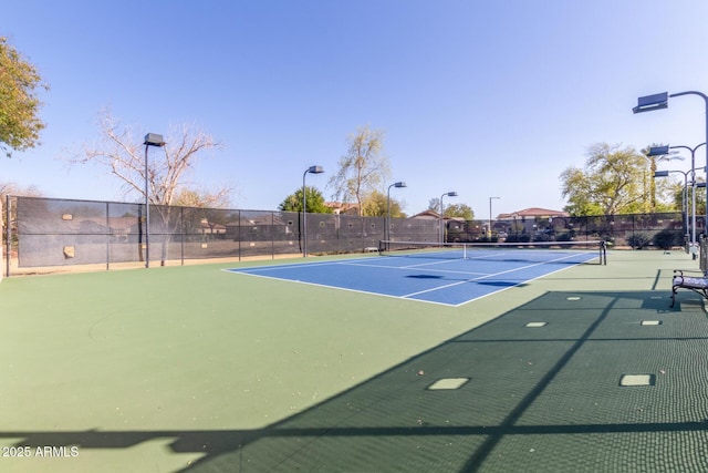 view of tennis court featuring community basketball court and fence