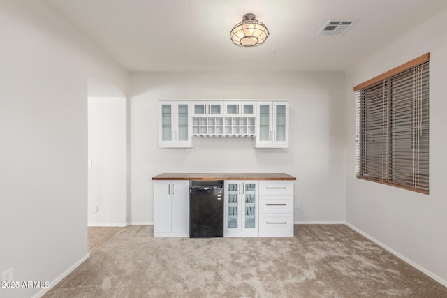 bar featuring a bar, light colored carpet, visible vents, and baseboards