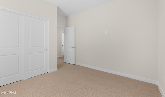 unfurnished bedroom featuring light carpet and a closet