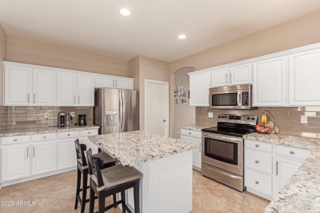 kitchen featuring appliances with stainless steel finishes, a center island, white cabinets, and a kitchen bar