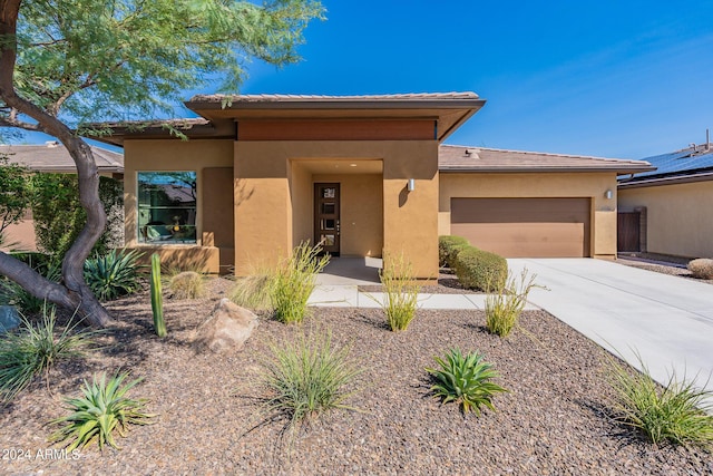 prairie-style house featuring stucco siding, a garage, a tiled roof, and concrete driveway