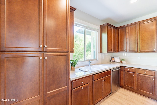 kitchen featuring stainless steel dishwasher, backsplash, light wood-type flooring, and sink