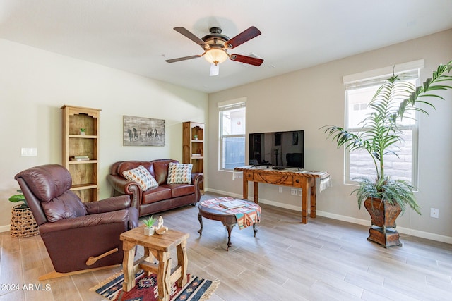 living room featuring baseboards, a ceiling fan, and light wood finished floors