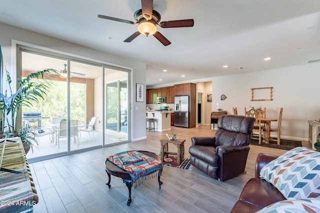living room featuring baseboards, ceiling fan, recessed lighting, and light wood finished floors