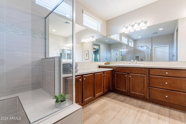 full bath with vanity, visible vents, wood finished floors, and a shower stall