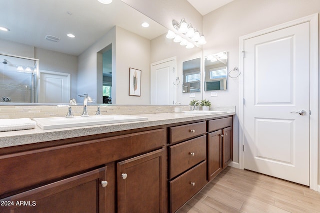 bathroom with a stall shower, double vanity, visible vents, and a sink