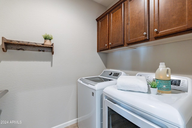 laundry area featuring independent washer and dryer, cabinet space, and baseboards