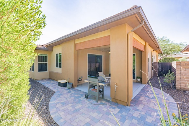 back of house featuring fence, ceiling fan, stucco siding, and a patio area