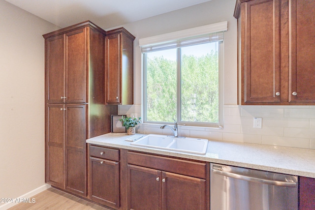 kitchen with stainless steel dishwasher, sink, light wood-type flooring, and tasteful backsplash