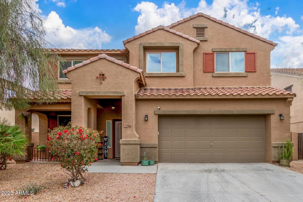 view of front facade featuring a tiled roof, stucco siding, an attached garage, and concrete driveway