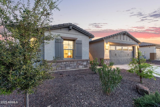 craftsman house with stucco siding, concrete driveway, an attached garage, stone siding, and a tiled roof