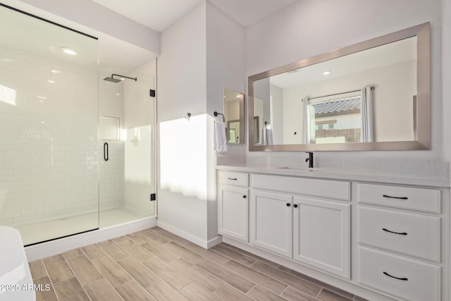 full bathroom with baseboards, a shower stall, vanity, and wood tiled floor