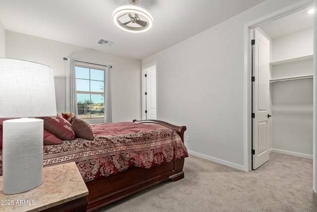 bedroom featuring light carpet, a spacious closet, visible vents, and baseboards