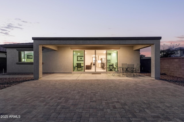 rear view of property featuring a patio area, fence, outdoor dining area, and stucco siding