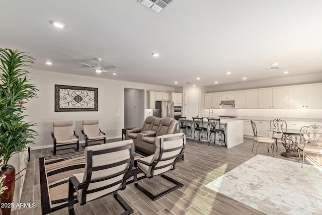 living area featuring wood finish floors, visible vents, baseboards, and recessed lighting