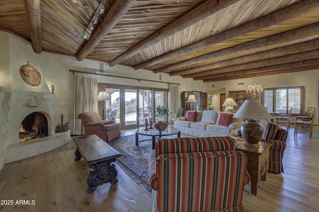 living room with beamed ceiling, hardwood / wood-style floors, an inviting chandelier, a fireplace, and wood ceiling