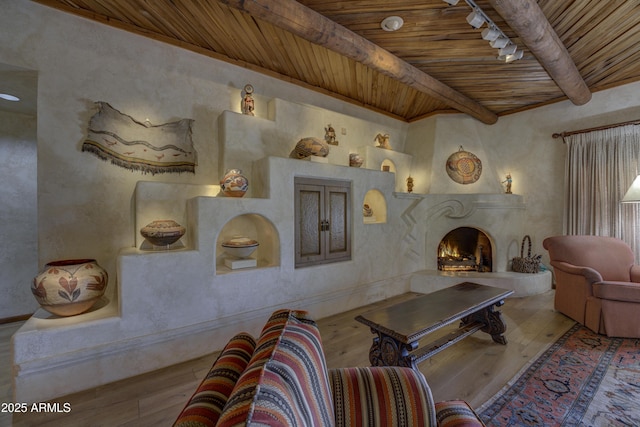 living room featuring a high end fireplace, track lighting, beamed ceiling, wooden ceiling, and hardwood / wood-style flooring