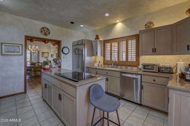 kitchen featuring a kitchen island, light tile patterned flooring, a sink, stainless steel appliances, and a notable chandelier