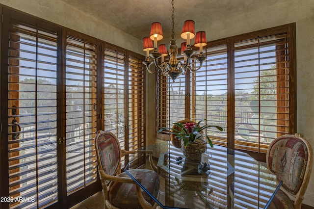 dining area with a textured wall, an inviting chandelier, and a healthy amount of sunlight