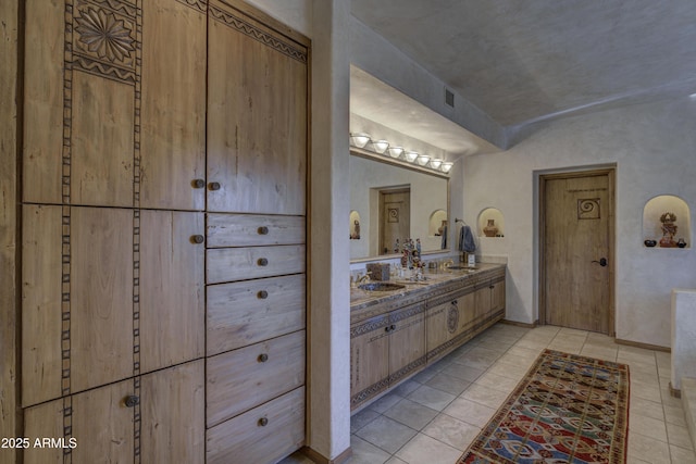 full bathroom with tile patterned floors, a sink, baseboards, and double vanity