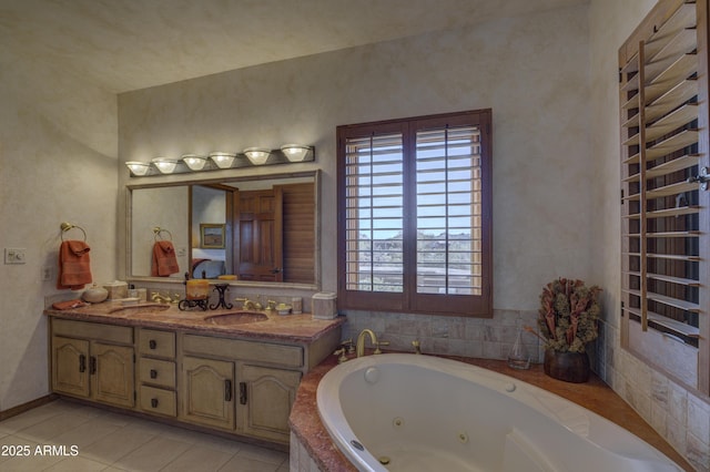 full bathroom with tile patterned flooring, a tub with jets, double vanity, and a sink