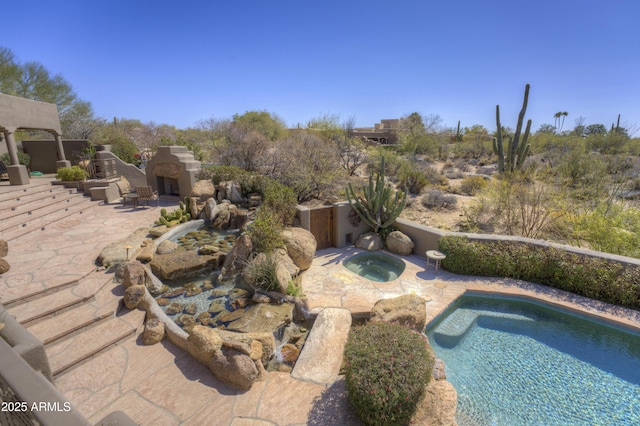 view of pool with an in ground hot tub, an outdoor fireplace, and a patio area