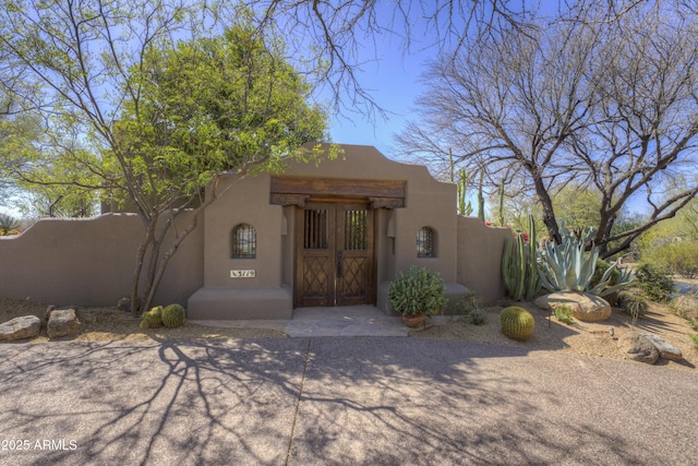 pueblo-style home featuring fence and stucco siding