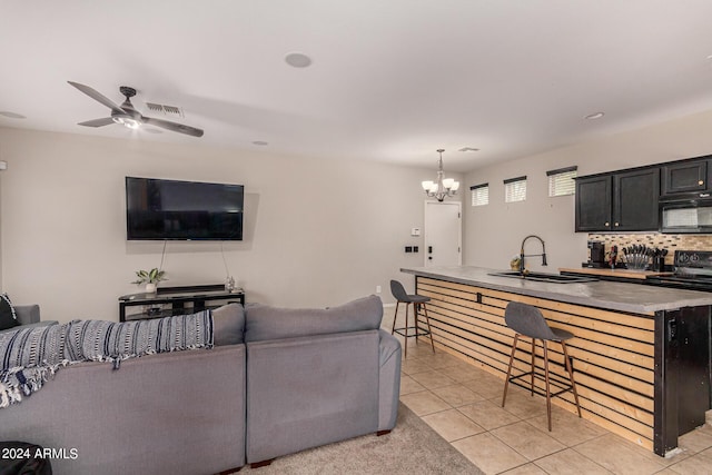 tiled living room with sink and ceiling fan with notable chandelier