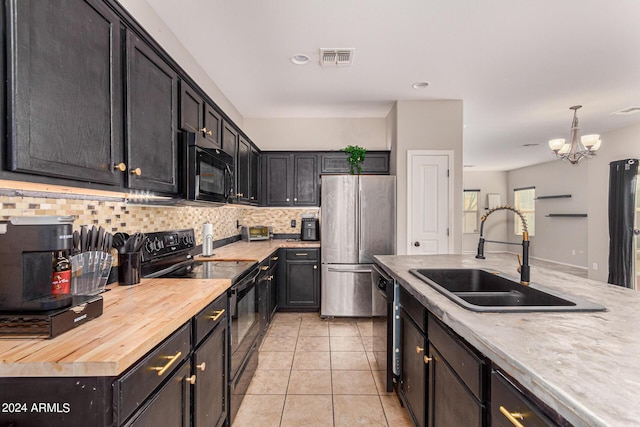 kitchen featuring sink, butcher block counters, hanging light fixtures, black appliances, and light tile patterned flooring