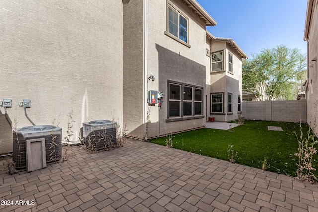 back of house with central AC, a patio area, and a lawn