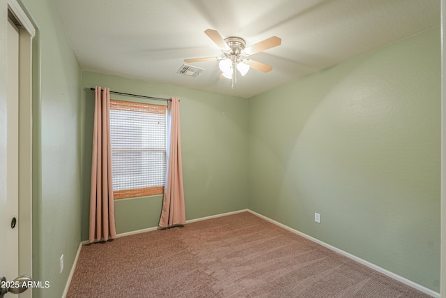 carpeted spare room featuring visible vents, ceiling fan, and baseboards