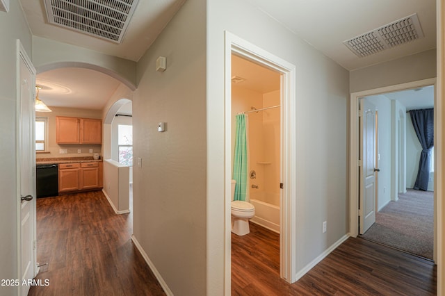 corridor featuring arched walkways, visible vents, and baseboards