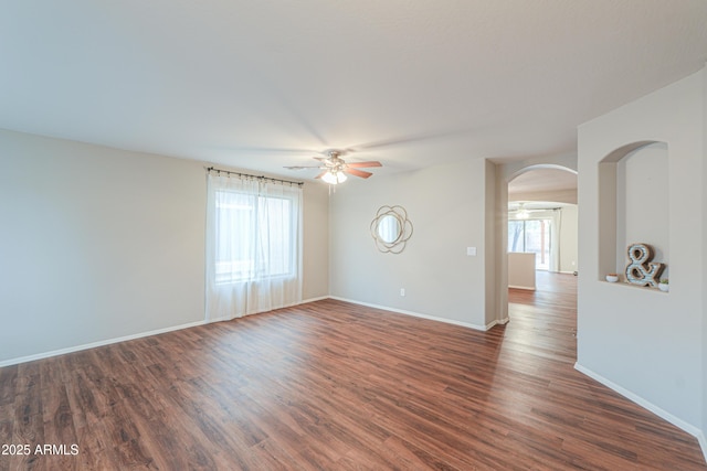 unfurnished room with a healthy amount of sunlight, ceiling fan, and dark wood-type flooring