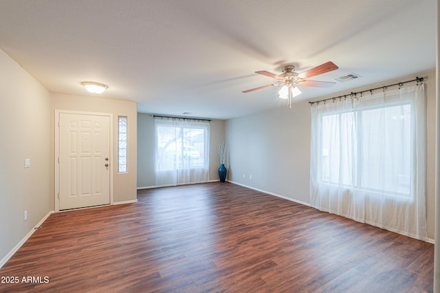 unfurnished room with a ceiling fan, visible vents, dark wood finished floors, and baseboards