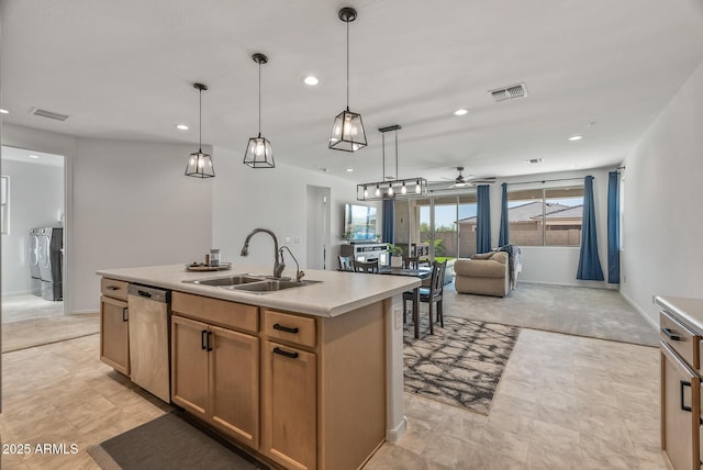 kitchen featuring washing machine and clothes dryer, visible vents, stainless steel dishwasher, and a sink